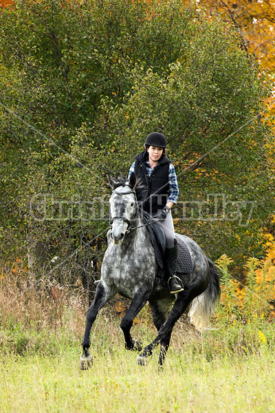 Young woman riding gray horse in the autumn colors