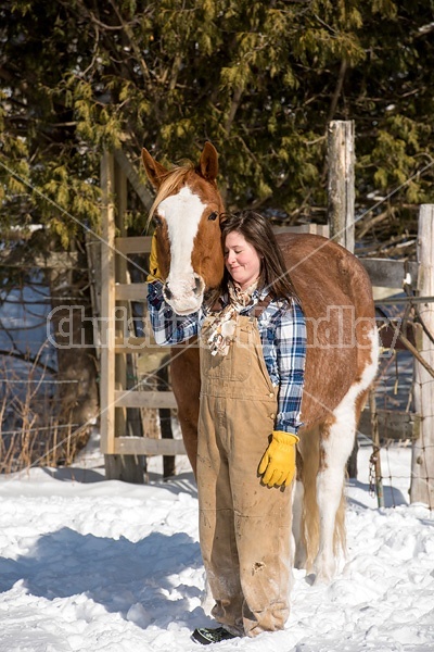 Young woman standing and hugging her horse