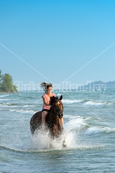 Young woman horseback riding in the surf of Lake Ontario. 