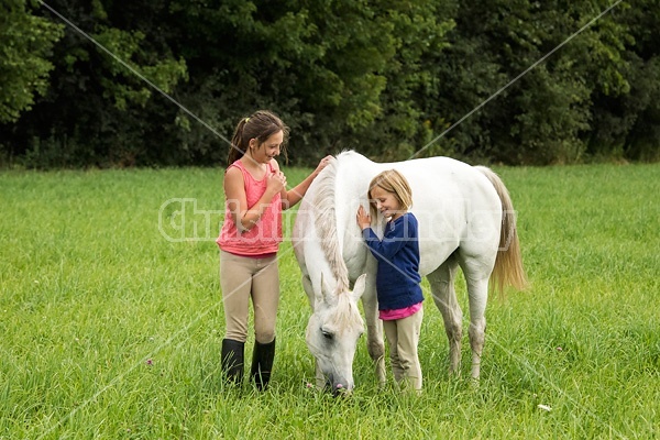 Potrait of two girls with a gray pony 