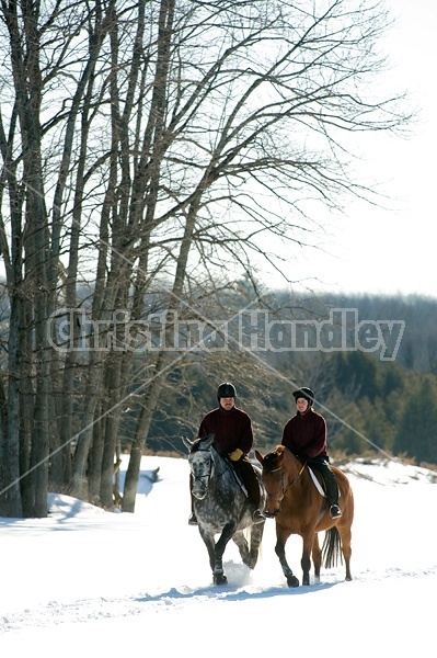 Husband and wife horseback riding through the deep snow