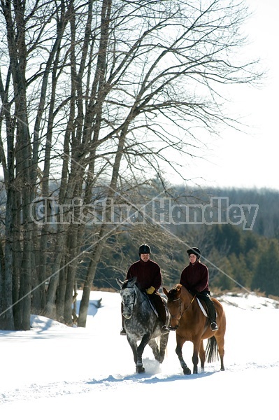 Husband and wife horseback riding through the deep snow