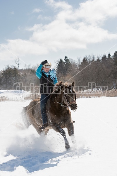 Young woman riding a horse bareback through deep snow