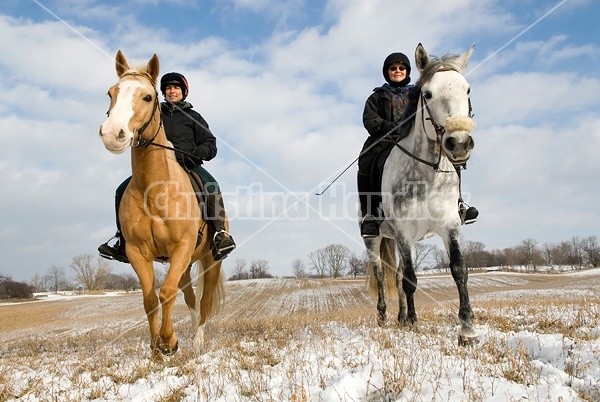 Two women horseback riding in the winter