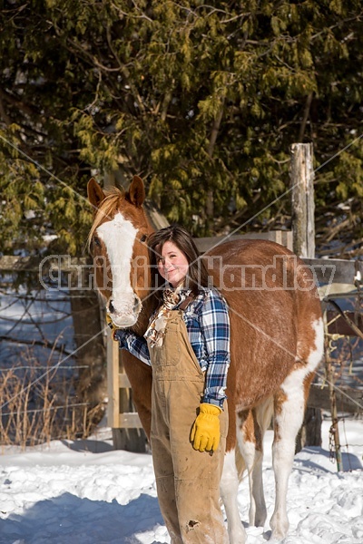 Young woman standing and hugging her horse