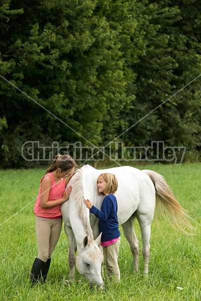 Potrait of two girls with a gray pony 