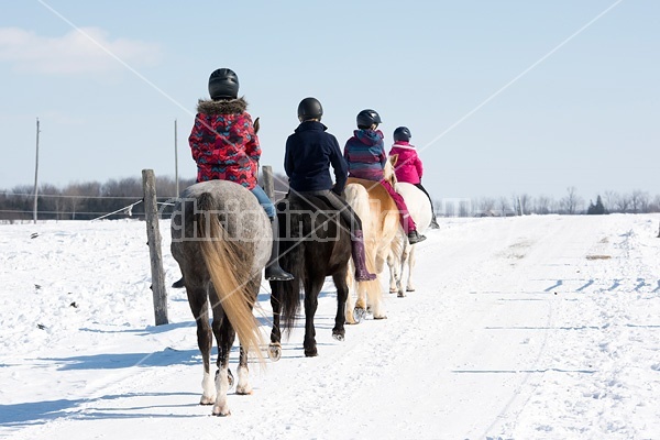 Four young girls riding their ponies bareback in the snow