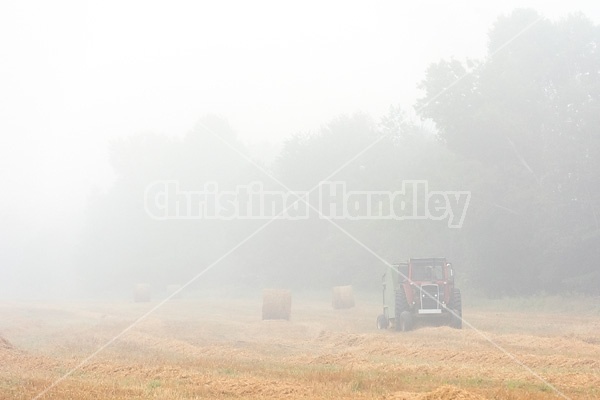 Farmer baling round bales of straw