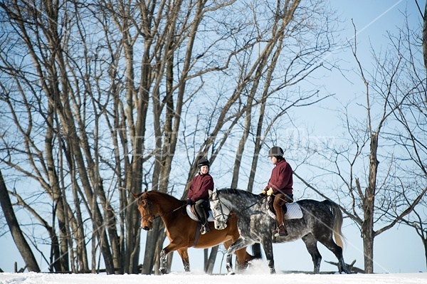 Husband and wife horseback riding through the deep snow