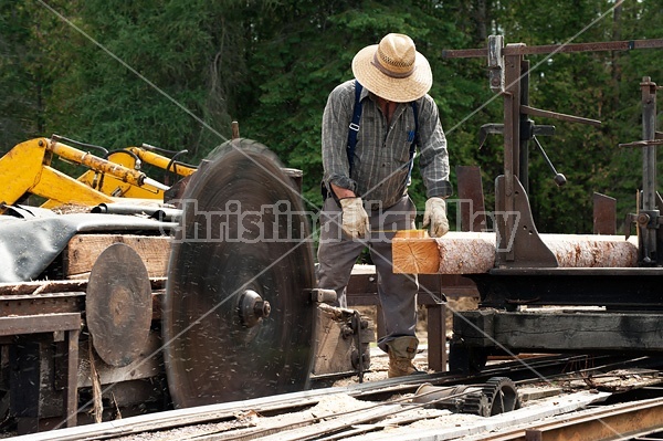 Man operating a circular saw mill on the farm