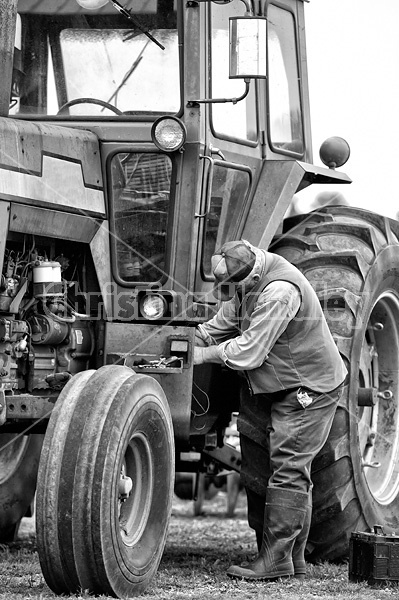 Farmer performing maintenance on tractor