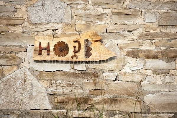 Hand made Hope garden art sign hanging on a barn stone wall