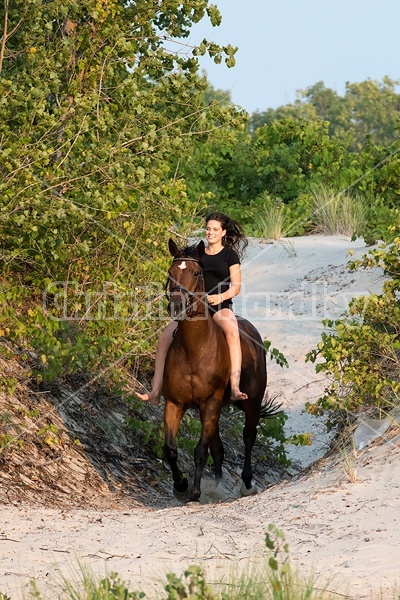 Young woman riding a hrose bareback in the sand