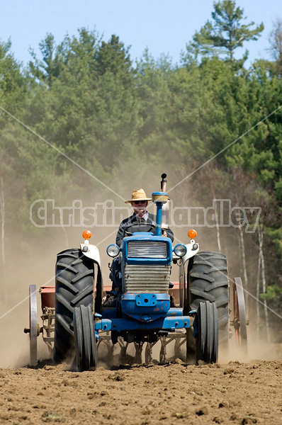 Man driving tractor pulling a seed drill planting oats