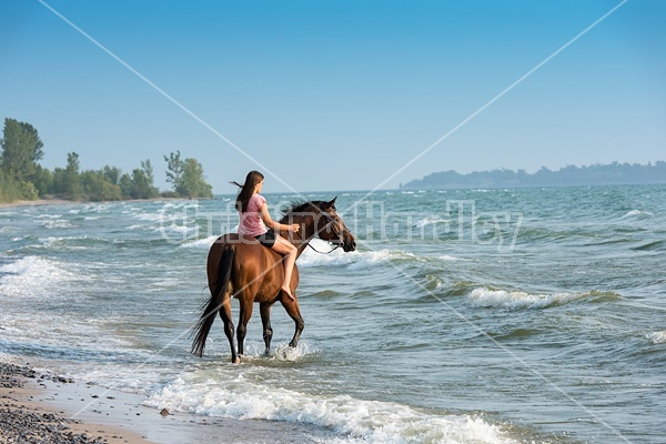 Young woman horseback riding in Lake Ontario