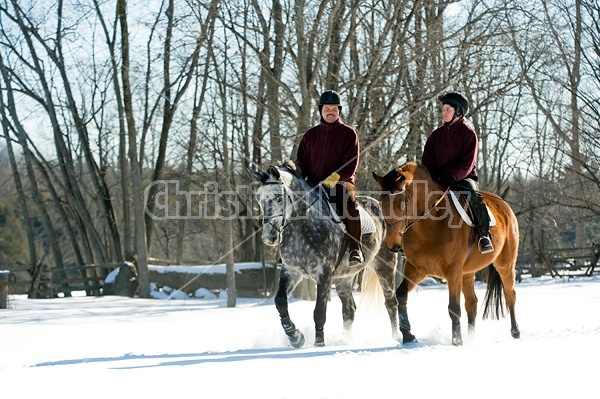 Husband and wife horseback riding through the deep snow