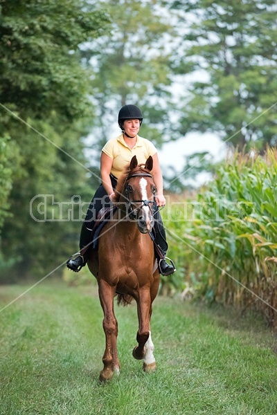 Young woman riding chestnut Thoroughbred horse.