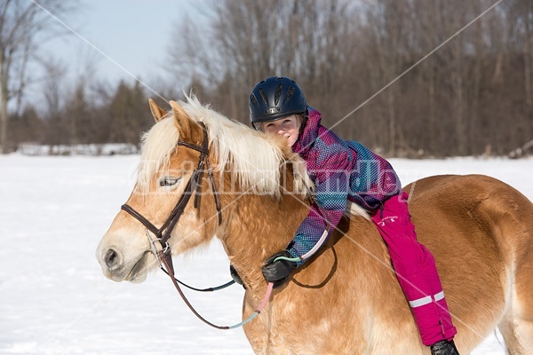 Young girl riding her pony bareback in the winter. 