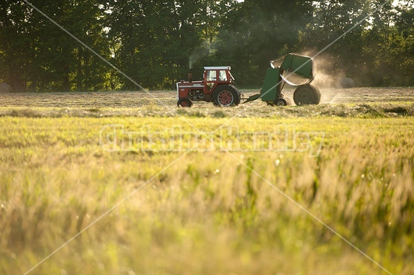 Farmer baling round bales of hay