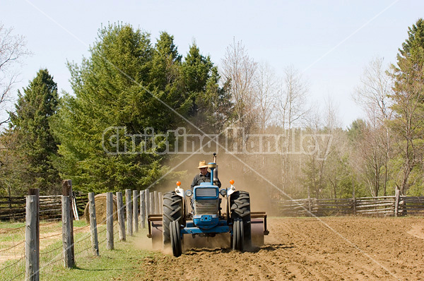 Farmer driving tractor pulling a land roller