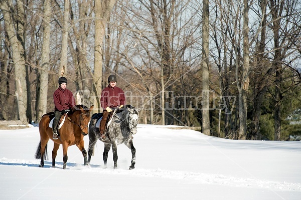 Husband and wife horseback riding through the deep snow