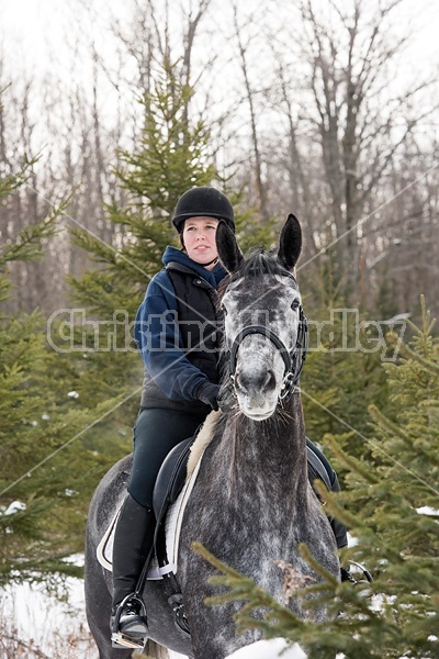 Woman riding Hanoverian mare through forest