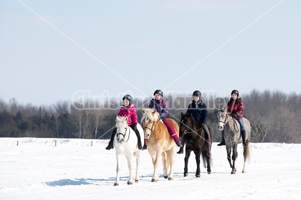 Four young girls riding their ponies bareback in the snow