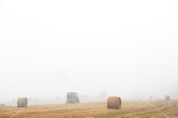 Farmer baling round bales of straw