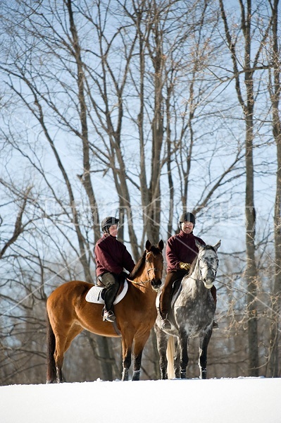 Husband and wife horseback riding through the deep snow