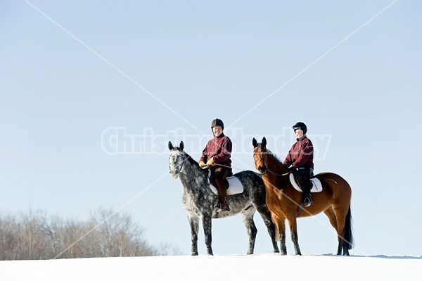 Husband and wife horseback riding through the deep snow