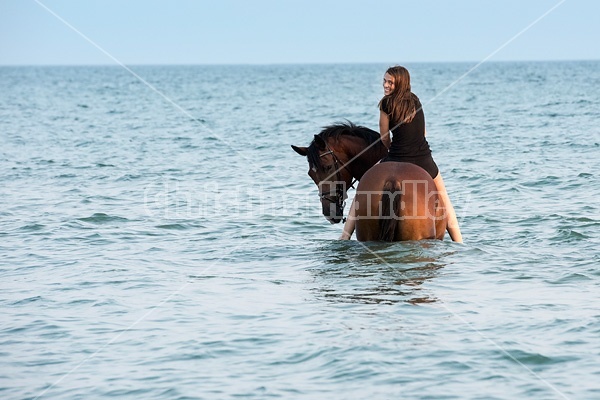 Young woman horseback riding in Lake Ontario