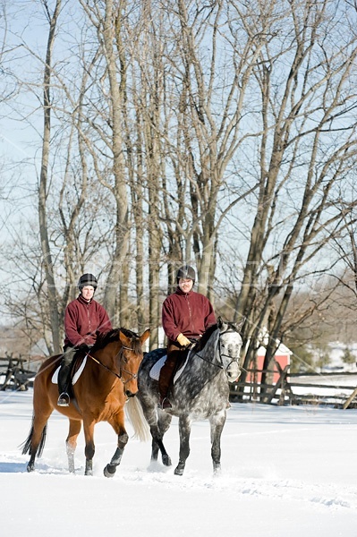 Husband and wife horseback riding through the deep snow