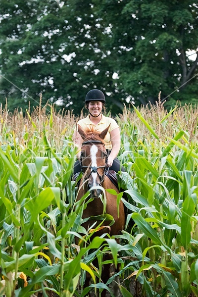 Young woman riding chestnut Thoroughbred horse.