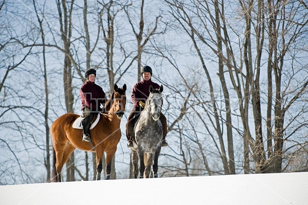 Husband and wife horseback riding through the deep snow