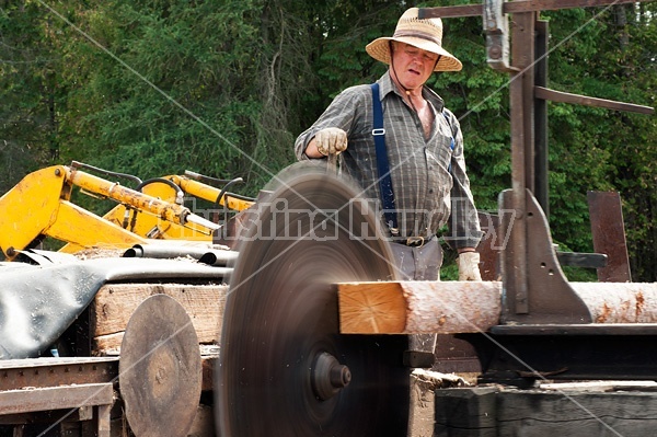 Man operating a circular saw mill on the farm