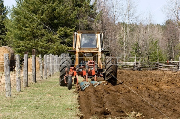 Farmer plowing field in the spring of the year with tractor and a three furrow plow