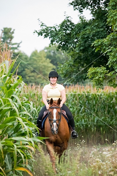 Young woman riding chestnut Thoroughbred horse.