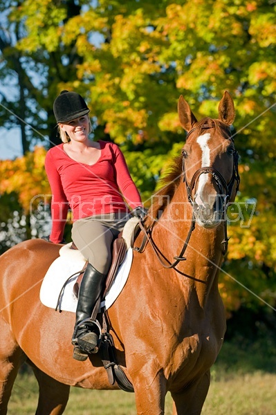 Young woman horseback riding in the fall of the year.