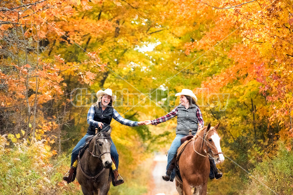 Two young women horseback riding through autumn colored scenery