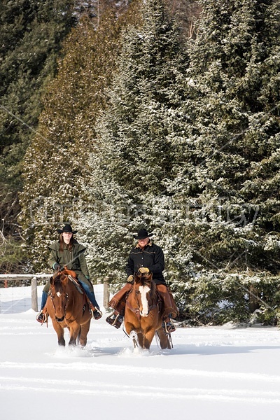 Man and woman horseback riding in the snow