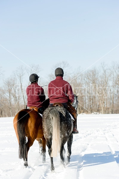 Husband and wife horseback riding through the deep snow