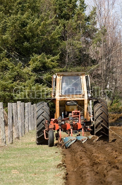 Farmer plowing field in the spring of the year with tractor and a three furrow plow