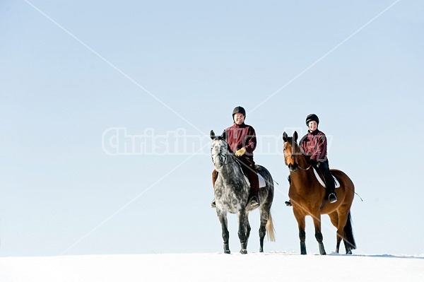 Husband and wife horseback riding through the deep snow