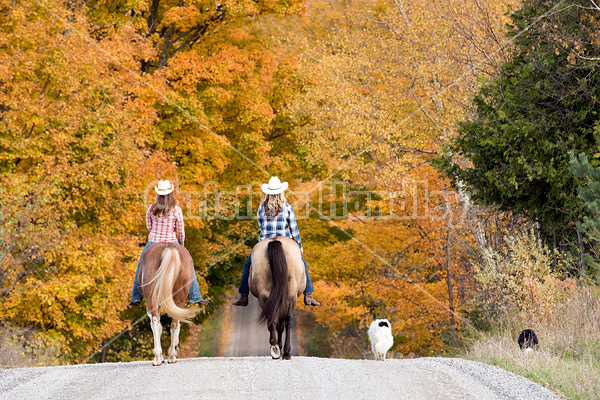 Two young women horseback riding through autumn colored scenery