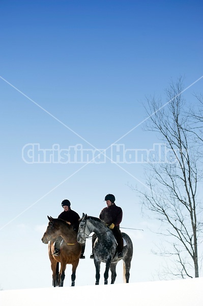 Husband and wife horseback riding through the deep snow