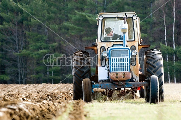 Farmer plowing field in the spring of the year with tractor and a three furrow plow