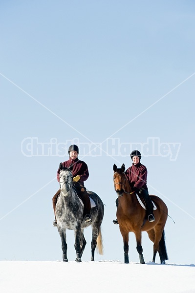 Husband and wife horseback riding through the deep snow