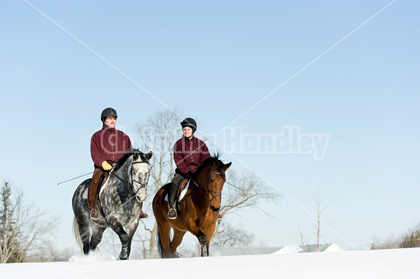 Husband and wife horseback riding through the deep snow