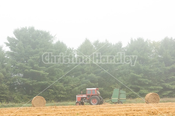 Farmer baling round bales of straw