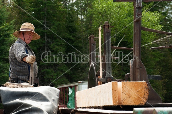 Man operating a circular saw mill on the farm